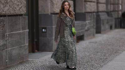 Anna Hiltrop seen wearing Boss green / beige / black print pattern pleated long dress, Boss brown suede leather jacket, Michael Kors green leather quilted crossbody bag and Gucci black leather laced boots, on February 16, 2024 in Berlin, Germany.