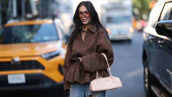 NEW YORK, NEW YORK - SEPTEMBER 09: Olga Sokolenko seen wearing black sunglasses with orange sheer lenses, large gold pearl necklace, Rogov brown pattern embroidered oversized jacket, blue denim destroyed baggy pants / jeans, Alaía beige leather Le Teckel small bag, during the New York Fashion Week, on September 09, 2024 in New York City. (Photo by Jeremy Moeller/Getty Images)