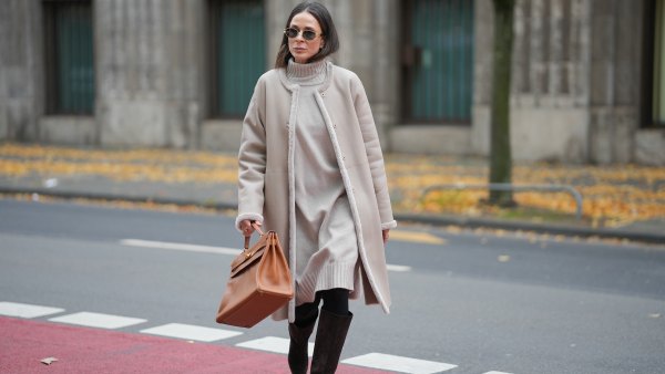Patricia Wirschke is seen wearing a beige shearling coat with fur-trimmed edges and a straight silhouette by Manzoni 24; a light beige ribbed cashmere turtleneck dress by Incentive; black tights; dark brown suede knee-high boots with a pointed toe by Massimo Dutti; a camel brown leather “Kelly 32” handbag with gold hardware by Hermès; oval metal-frame sunglasses called “Triomphe Metal 01” by Céline; her brown hair is worn straight with a middle part on November 10, 2025 in Duesseldorf, Germany.