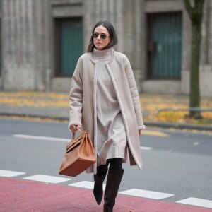 Patricia Wirschke is seen wearing a beige shearling coat with fur-trimmed edges and a straight silhouette by Manzoni 24; a light beige ribbed cashmere turtleneck dress by Incentive; black tights; dark brown suede knee-high boots with a pointed toe by Massimo Dutti; a camel brown leather “Kelly 32” handbag with gold hardware by Hermès; oval metal-frame sunglasses called “Triomphe Metal 01” by Céline; her brown hair is worn straight with a middle part on November 10, 2025 in Duesseldorf, Germany.