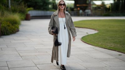 COPENHAGEN, DENMARK - AUGUST 6: Louisa Theresa Grass wears oversized round sunglasses, a long taupe trench coat over a white strapless maxi dress, a long black tassel necklace, carries a black woven clutch with an oversized tassel and wears black loafers outside the Collina Strada show during day 4 of Copenhagen Fashion Week Spring Summer 2027 on August 6, 2026 in Copenhagen, Denmark. (Photo by Moritz Scholz/Getty Images)
