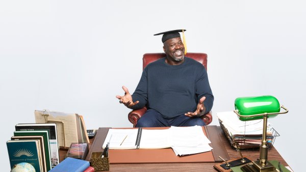 Shaquille O'Neal in cap and gown behind a school desk