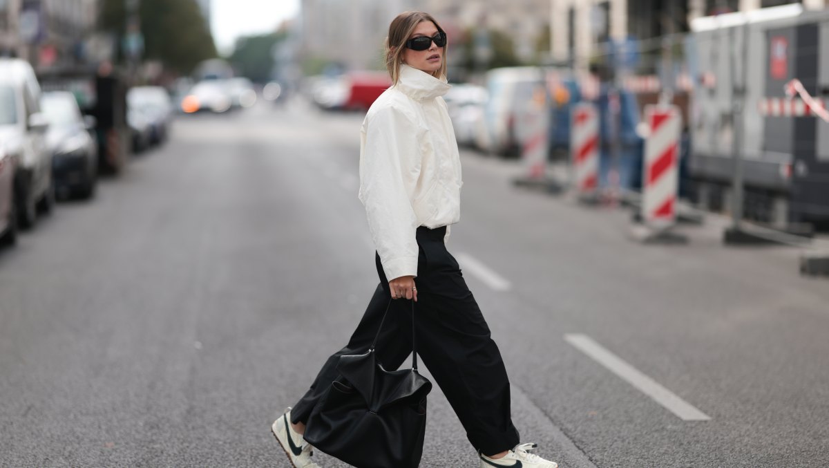 BERLIN, GERMANY - AUGUST 28: Sophia Geiss seen wearing an ivory COS windbreaker jacket with a high funnel neck and voluminous sleeves is paired with black COS wide-leg pleated trousers, white Nike x Jacquemus sneakers, a structured black COS leather bag and Mango sunglasses complete the look on August 28, 2026 in Berlin, Germany. (Photo by Jeremy Moeller/Getty Images)