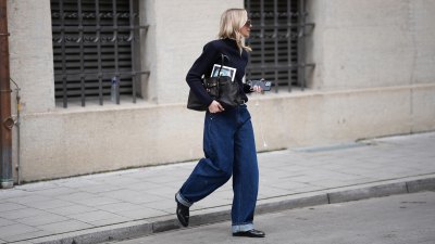 MUNICH, GERMANY - FEBRUARY 18: Mirja Klein is seen wearing a navy fine knit turtleneck sweater with long sleeves and a fitted silhouette from COS; dark wash baggy jeans with a relaxed oversized barrel fit and rolled-up legs from Dark Park; a slim black leather belt with silver buckle; black polished leather loafers with a sleek rounded toe and slim profile from COS; a black „Aventure“ nappa leather bag with gold hardware, chain link details and a belted detail in the front closure from Miu Miu; oversized shield sunglasses with a thick transparent acetate frame and brown tinted lenses from Bottega Veneta; oversized brown shield sunglasses with dark tinted lenses and a thick glossy frame from MM6 Maison Margiela; holding an iPhone smartphone and wearing white wired earphones; her blonde hair is worn long and wavy with a center part on February 18, 2026 in Munich, Germany. (Photo by Moritz Scholz/Getty Images)