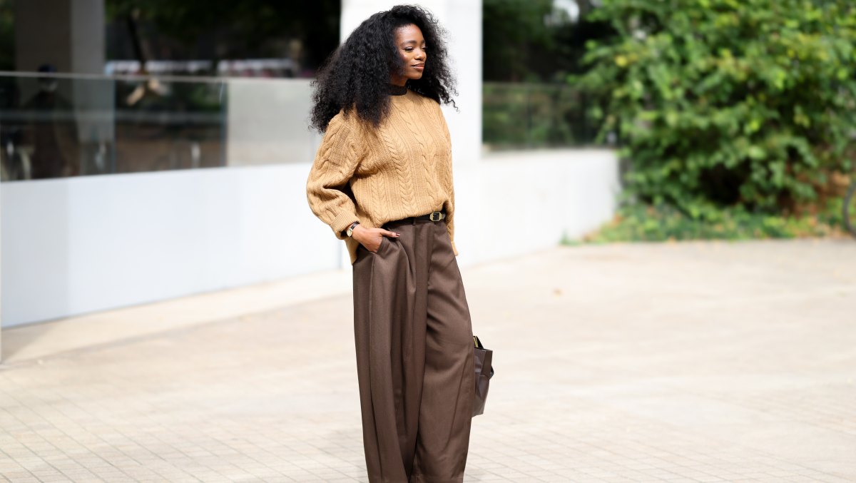 LONDON, ENGLAND - SEPTEMBER 18: Nadine Petzke is seen wearing a camel cable knit sweater over a dark brown high neck layer; tailored dark brown wide leg trousers with a black leather belt; black leather square toe flats; wearing gold hoop earrings and stacked bracelets; voluminous natural curly hair worn loose outside the Marks & Spencer show during London Fashion Week September 2026 on September 18, 2026 in London, England. (Photo by Moritz Scholz/Getty Images)