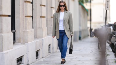 Diane Batoukina @diaanebt wears black sunglasses from Chanel, a white t-shirt, a beige gray oversized blazer jacket from Anine Bing, navy blue denim rolled-up large pants from Rouje, a black shiny grained leather Timeless handbag from Chanel, black shiny leather loafers mules from Massimo Dutti, during a street style fashion photo session, on April 15, 2022 in Paris, France.