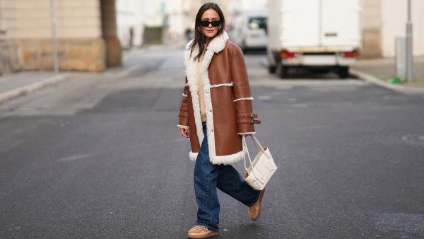 BERLIN, GERMANY - NOVEMBER 25: Laura Noltemeyer is seen wearing a shearling lining coat in a rich cognac tone with an oversized straight silhouette, wide lapels and buckle-strap cuff detailing on the sleeves from Max&Co; layered underneath is a soft beige wool-blend knit sweater with a ribbed crew neckline and ribbed trims from Sézane; dark-blue straight-leg denim trousers with a classic fit from By Aylin Koenig; beige suede winter boots with a rounded toe, exposed stitching and shearling lining from Inuikii; a white structured leather top-handle bag in an intrecciato weave and trapeze silhouette called “Intrecciato Tote” from Bottega Veneta; chunky sculptural gold earrings from Zara; black angular acetate sunglasses with a thick frame and dark lenses from Saint Laurent; her dark-brown hair is worn straight with a center part on November 25, 2025 in Berlin, Germany. (Photo by Moritz Scholz/Getty Images)