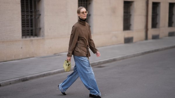 MUNICH, GERMANY - MARCH 20: Marlies Pia Pfeifhofer is seen wearing a short brown trench jacket with a wraparound tie belt, high funnel neck, dropped shoulders and a rolled up sleeves from COS; light blue wide leg denim jeans with a relaxed oversized drape and rolled up cuffs from Agolde; black pointed toe suede ballet shoes with a low block heel from Sézane; a small pistachio green leather „Le Roseau“ bag with a small handle, silver hardware and structured pouch silhouette from Longchamp; angular sunglasses with brown faded tinted lenses and a thick transparent acetate frame from Chimi; tiny silver hoop earrings from Monica Vinader; a silver stainless steel „Air-King“ wristwatch from Rolex; her blonde hair is styled in a low ponytail with middle parting on March 20, 2026 in Munich, Germany. (Photo by Moritz Scholz/Getty Images)