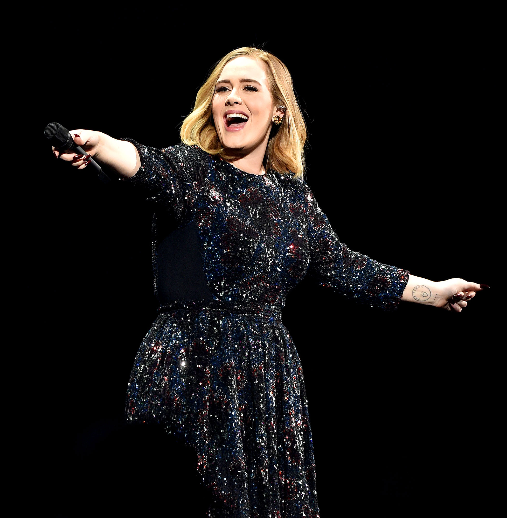 Adele hides behind her handbag as she sings along to her own song