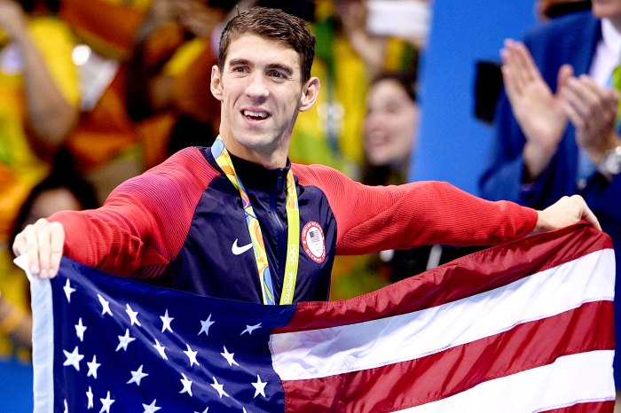 USA's gold medallist Michael Phelps holds the US flag after the podium ceremony of the Men's swimming 4 x 100m Medley Relay Final at the Rio 2016 Olympic Games at the Olympic Aquatics Stadium in Rio de Janeiro on August 13, 2016.