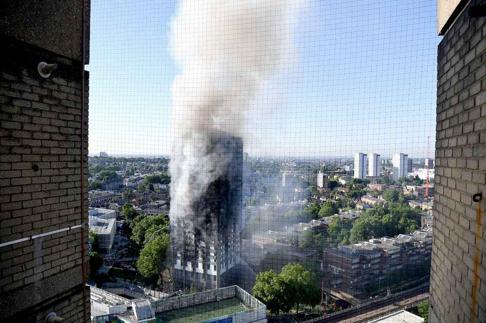 Smoke rises from the building after a huge fire engulfed the 24 storey residential Grenfell Tower block in Latimer Road, West London in the early hours of this morning on June 14, 2017 in London, England.