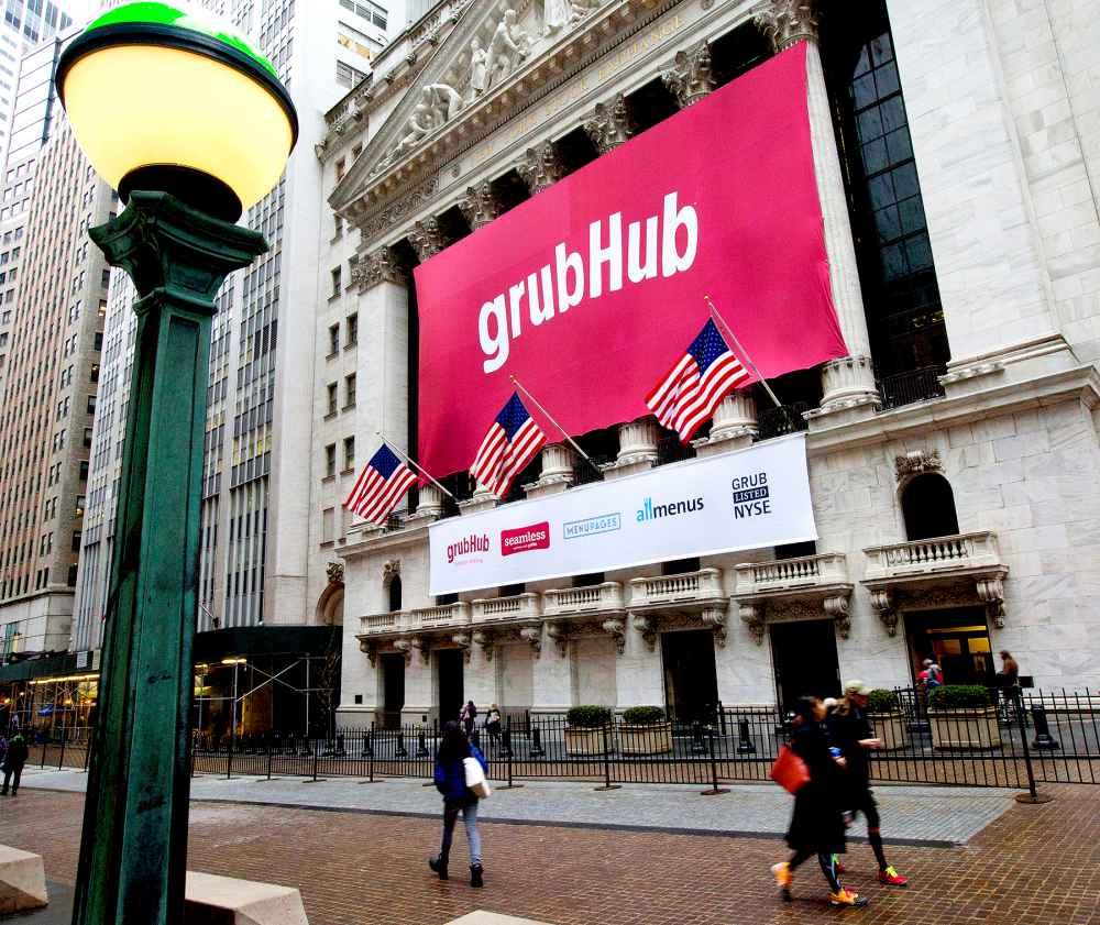 Pedestrians walk past a GrubHub Inc. banner on the exterior of the New York Stock Exchange in New York.