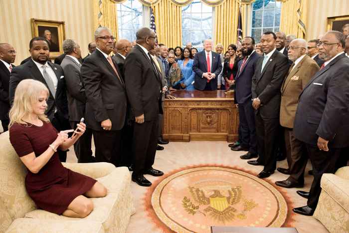 Counselor to the President Kellyanne Conway (L) checks her phone after taking a photo as US President Donald Trump and leaders of historically black universities and colleges pose for a group photo in the Oval Office of the White House before a meeting with US Vice President Mike Pence February 27, 2017 in Washington, DC.