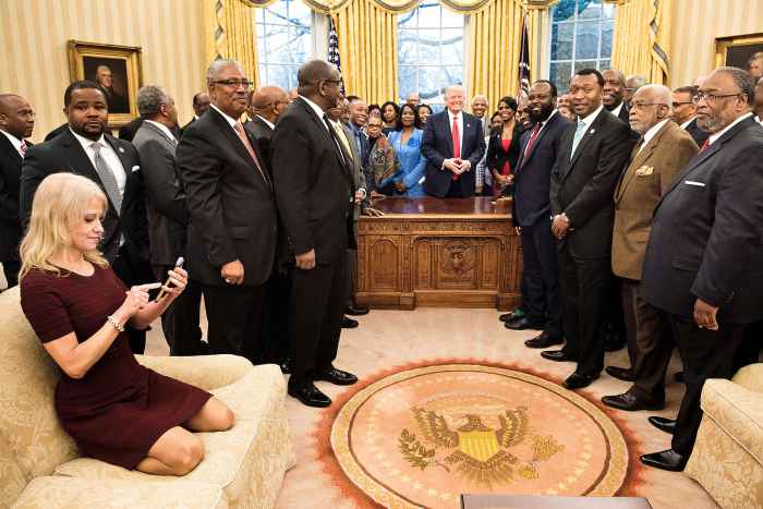 Counselor to the President Kellyanne Conway (L) checks her phone after taking a photo as US President Donald Trump and leaders of historically black universities and colleges pose for a group photo in the Oval Office of the White House before a meeting with US Vice President Mike Pence February 27, 2017 in Washington, DC.