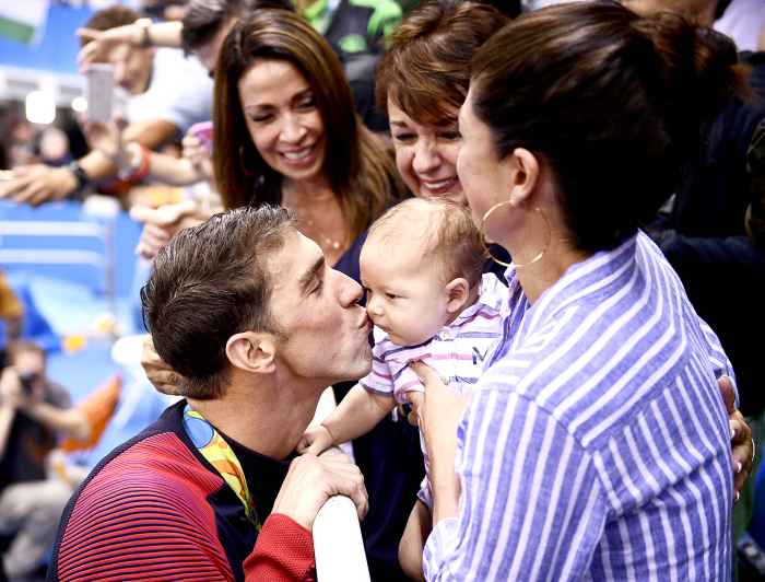USA's Michael Phelps (L) kisses his son Boomer next to his partner Nicole Johnson (R) and mother Deborah (C) after he won the Men's 200m Butterfly Final during the swimming event at the Rio 2016 Olympic Games at the Olympic Aquatics Stadium in Rio de Janeiro on August 9, 2016.