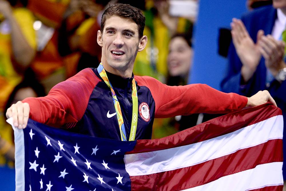 USA gold medalist Michael Phelps holds the U.S. flag after the podium ceremony of the men's swimming 4x100m Medley Relay Final at the Rio 2016 Olympic Games at the Olympic Aquatics Stadium in Rio de Janeiro on August 13, 2016.