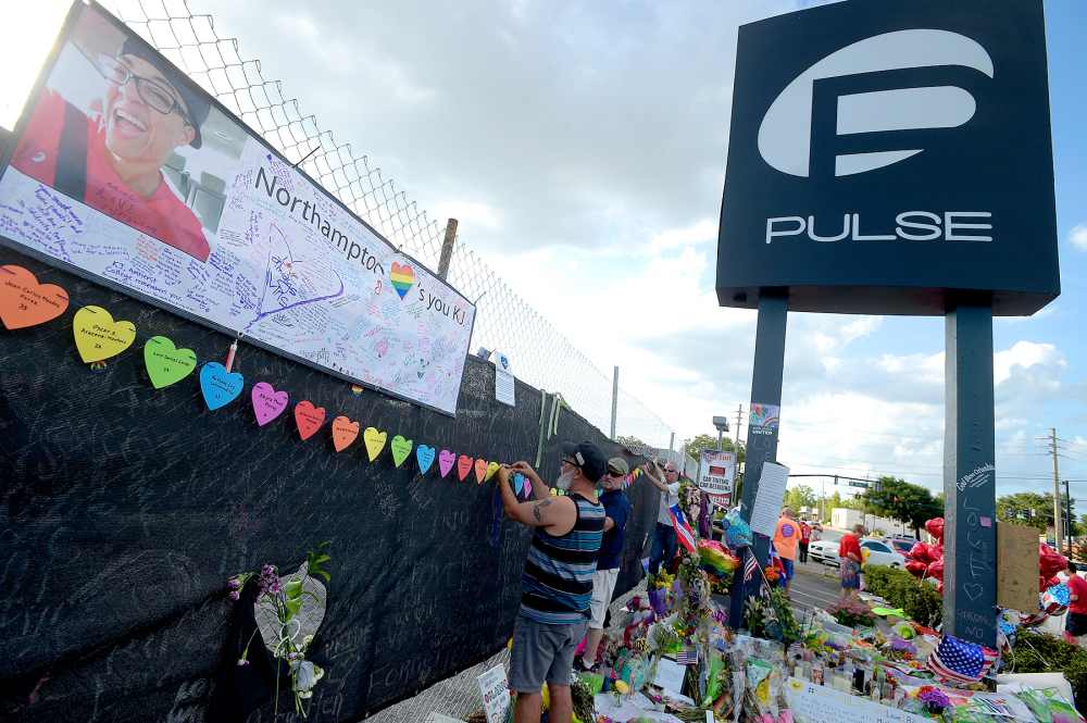 Mourners visit a makeshift memorial for victims of the Pulse nightclub shooting in front of the location, Saturday, June 25, 2016, in Orlando.