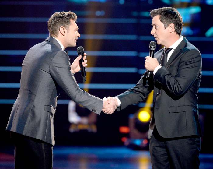 Host Ryan Seacrest and Brian Dunkleman speak on stage.