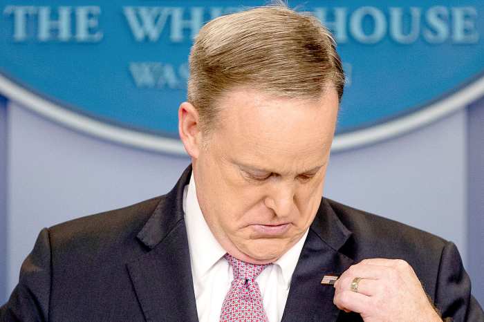 White House press secretary Sean Spicer adjusts his American flag pin after he was told that it was upside down, Friday, March 10, 2017, during the daily press briefing at the White House in Washington.