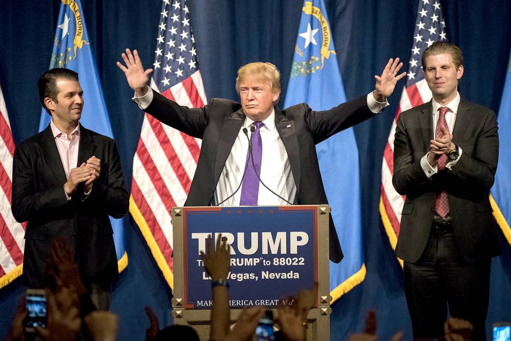 Donald Trump, center, gestures as his sons Donald Trump Jr., left, and Eric Trump, right, applaud during a caucus night rally in Las Vegas on Tuesday, Feb. 23, 2016.