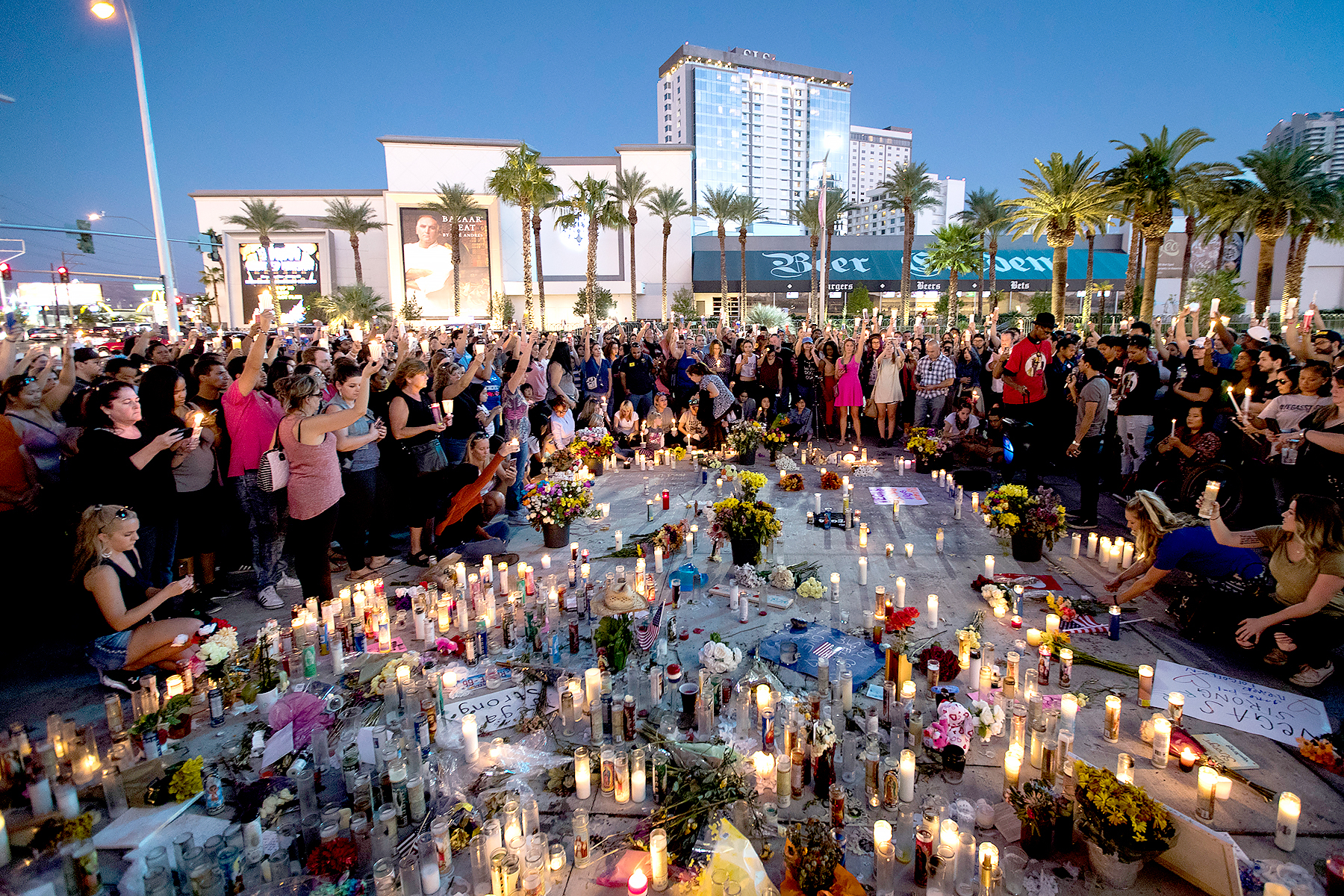 Mourners hold their candles in the air during a moment of silence during a vigil to mark one week since the mass shooting at the Route 91 Harvest country music festival, on the corner of Sahara Avenue and Las Vegas Boulevard at the north end of the Las Vegas Strip, on October 8, 2017 in Las Vegas, Nevada.