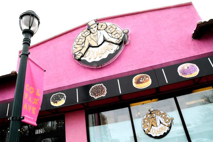 The company sign hangs over the windows of the storefront of Voodoo Doughnuts on East Colfax Avenue in Denver on Tuesday, April 4, 2017.